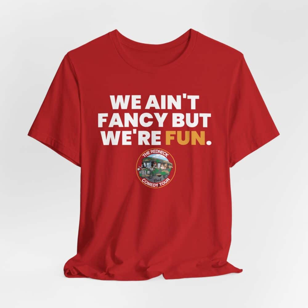 We Ain't Fancy Tshirt: Red t-shirt featuring white and yellow text "WE AIN'T FANCY BUT WE'RE FUN" with a small circular "The Redneck Comedy Tour" graphic above.