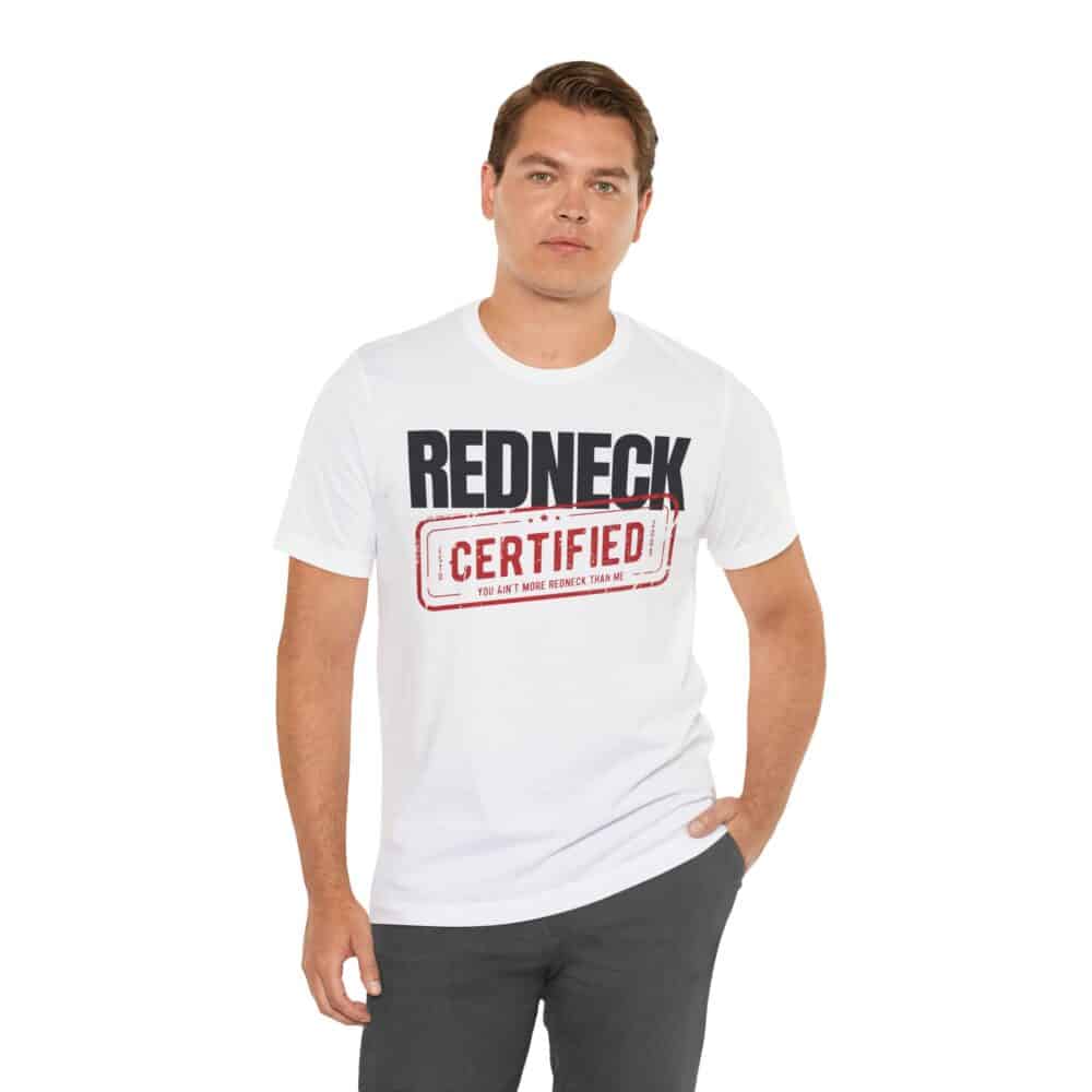 A man stands against a white background wearing the Redneck Certified Tshirt, featuring "Redneck Certified" in bold black and red text.