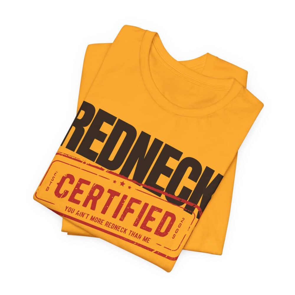 A folded yellow Redneck Certified Tshirt with "REDNECK CERTIFIED" and "YOU AIN'T MORE REDNECK THAN ME" on the front.