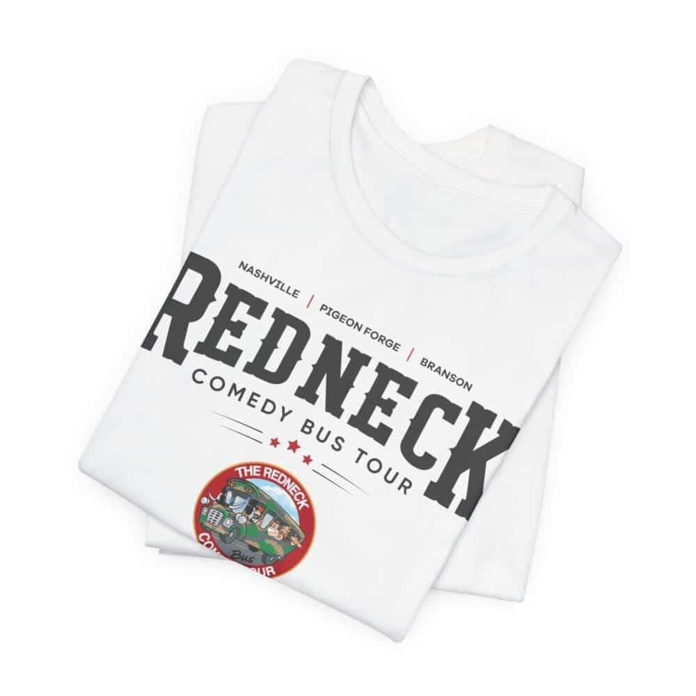 Redneck Comedy Bus Tour Tshirt: Folded white shirt featuring "Redneck Comedy Bus Tour" text, locations, and a colorful logo with cartoon characters and a bus.