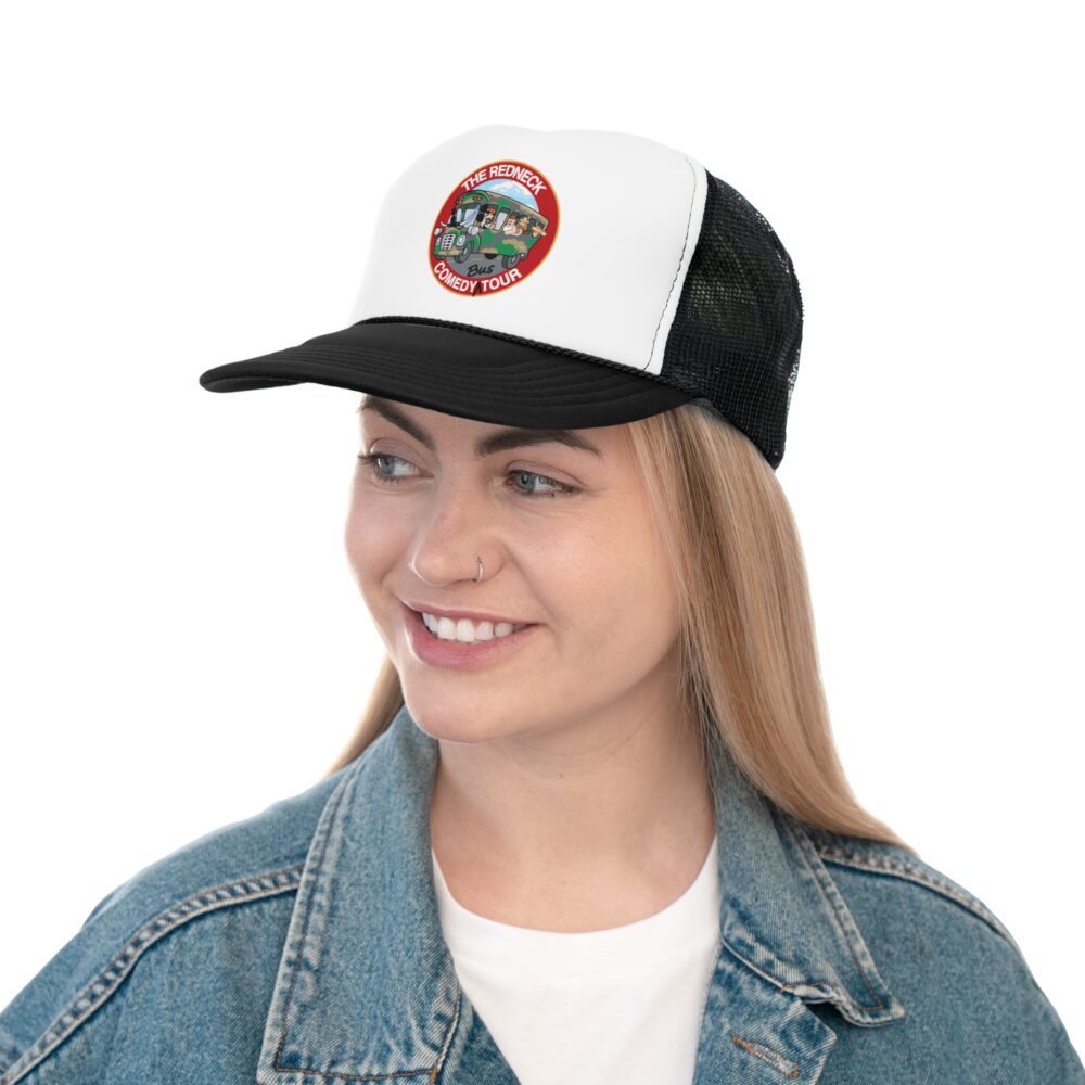 A woman smiles and looks to the side while wearing The Redneck Comedy Tour Trucker Cap - Black & White, featuring a colorful round patch, paired with a denim jacket.