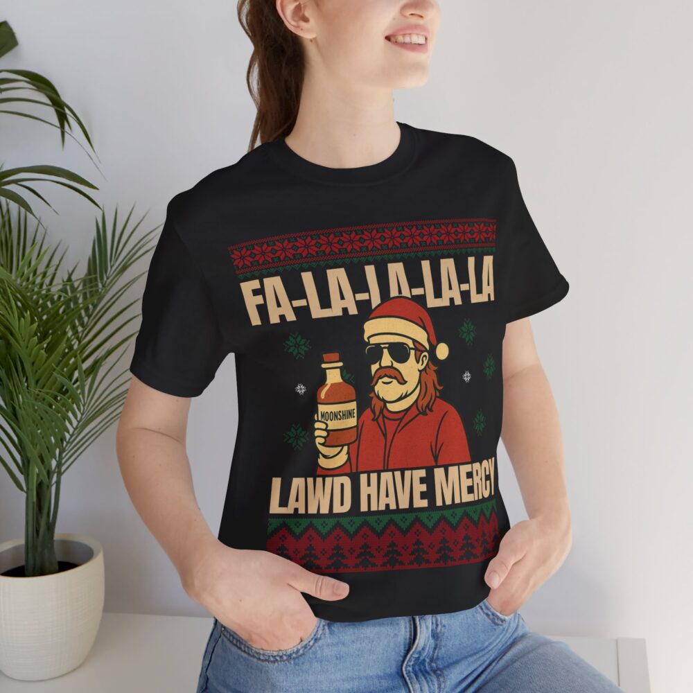 A woman wearing the Christmas Ugly Sweater Redneck Tshirt featuring a cartoon man in a Santa hat holding a bottle and the text "FA-LA-LA-LA-LA LAWD HAVE MERCY.