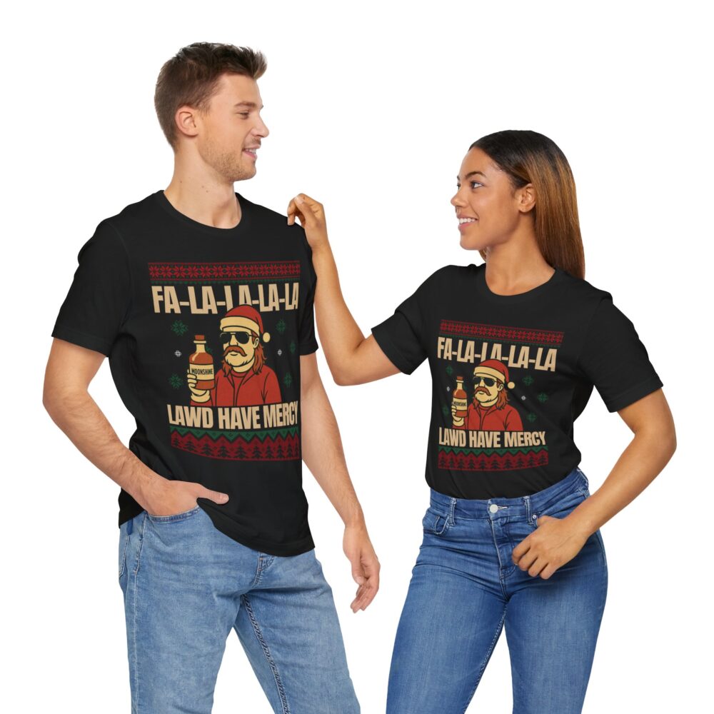 A man and woman stand smiling side by side, both wearing matching Christmas Ugly Sweater Redneck Tshirts with a festive graphic and the text “FA-LA-LA-LA-LA LAWD HAVE MERCY.”.